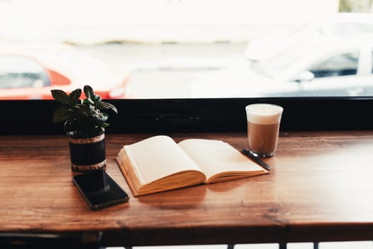 Cup of coffee, notebook, phone at table in cafe. Blurred background. High quality photo