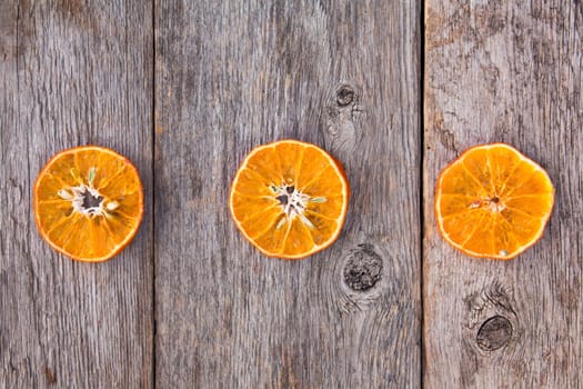 Three orange slices on a wooden background. The benefits of fruit.