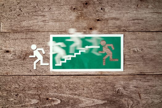 Exit sign on old wooden wall with man figure running to doorway