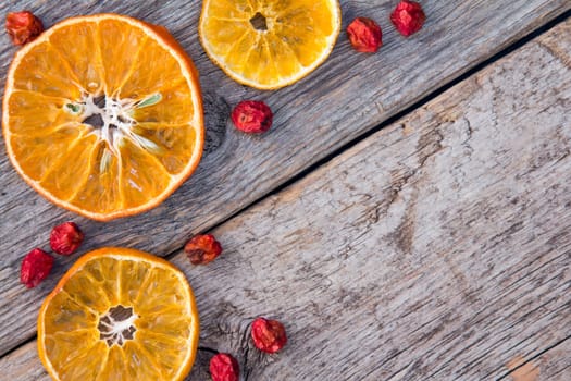 Dried oranges with ashberry on the old wooden background.