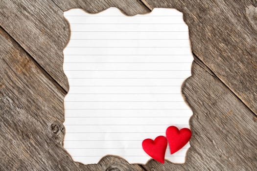 Valentine's day background with burned paper piece and red hearts