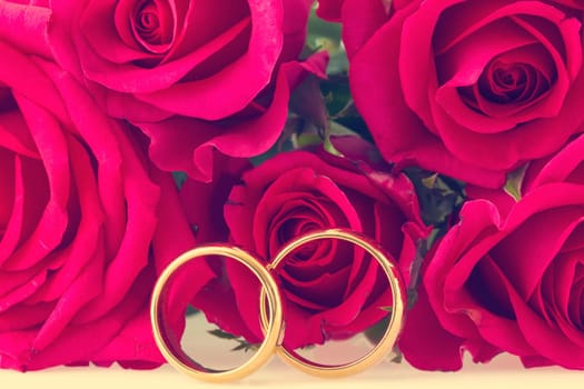 Wedding rings with red roses on background