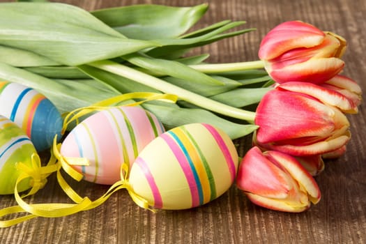 Easter eggs and fresh spring tulips on wooden background