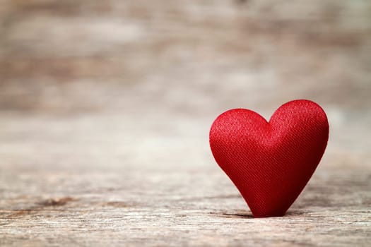 Red heart made of fabric on vintage background