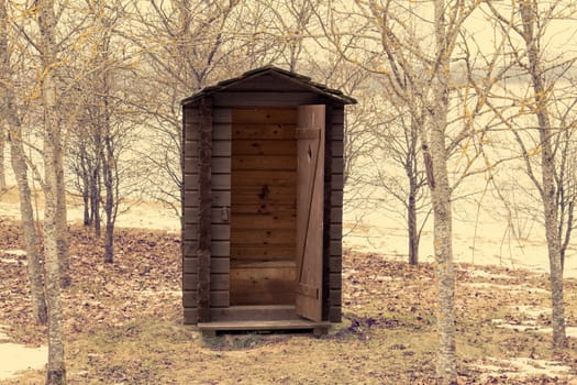 Wooden outdoor toilet with opened door in the park
