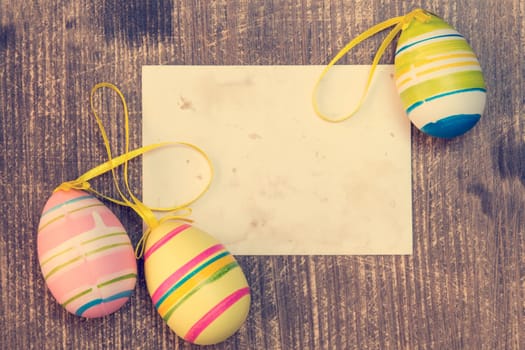 Colorful easter eggs and blank card on wooden background