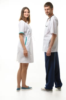 A man and a woman in medical clothes stand with their backs and turned around looking at the frame