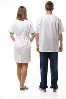 A man and a woman in medical clothes stand with their backs, full height