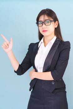 Asian business woman in suit with finger pointing up on blue background