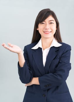Asian woman in suit open hand palm gestures with empty space isolated on gray background
