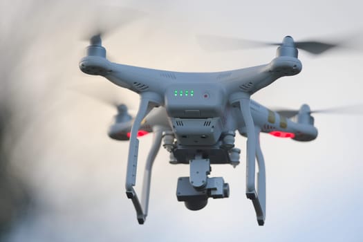 Great Malvern, United Kingdom, 27th December, 2020: Rear view of a white quadcopter drone with lights, against blue evening sky. Motion blur propeller