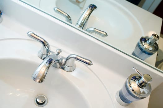 Close-up of a faucet and a soap dispenser on a bathroom sink