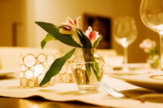 Close-up of a flower vase with candlestick holders on a dining table