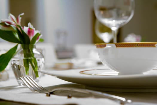 Close-up of a flower vase and a soup bowl on a dining table