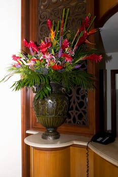 Flower vase and a telephone on a cabinet