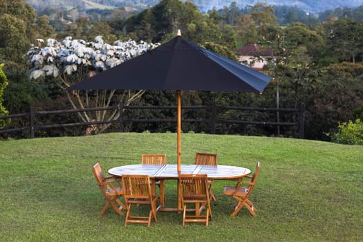 Table and chairs under a patio umbrella in a lawn