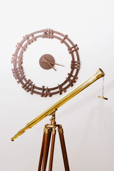 Telescope on a tripod with a clock on a wall