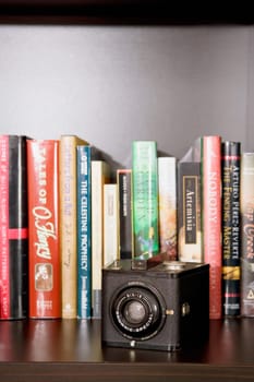 Close_up of a camera in front of books in a shelf