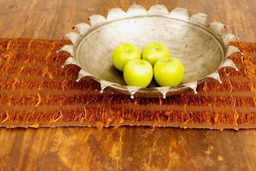 Close_up of four apples in a bowl on a dining table