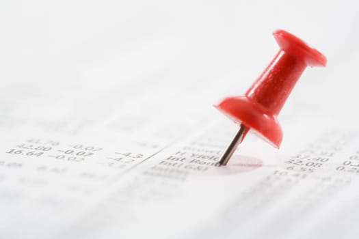 Close_up of a straight pin on a financial newspaper
