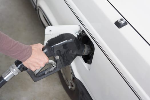 Woman refueling a car at a gas station