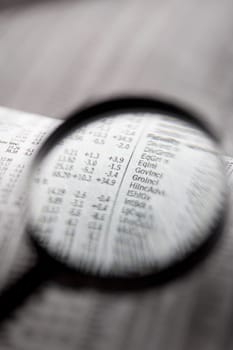 Close_up of a financial newspaper and a magnifying glass