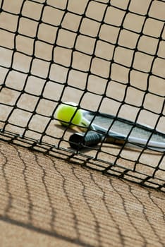 Tennis ball and a tennis racket behind a tennis net