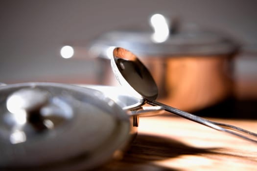 Close-up of bowls with lids and a ladle on a table