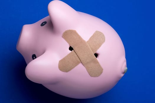 High angle view of adhesive bandages covering the slot of a piggy bank
