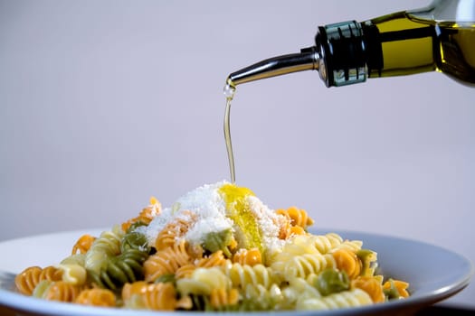 Olive oil being poured on a plate of pasta