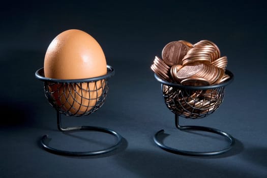 Close-up of an egg and coins in two egg cups