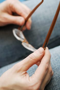Close-up of a personŽs hands holding a pair of eyeglasses
