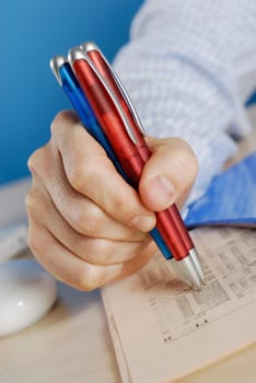 Close-up of a personŽs hand holding ballpoint pens on a sheet of paper