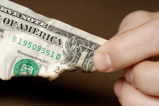 Close-up of a personŽs fingers holding a burnt American dollar bill