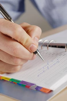 Close-up of a personŽs hand writing on a spiral notebook