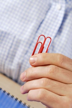 Close-up of a personŽs hand holding two paper clips