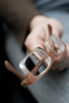 Close-up of a personŽs hand holding a pair of eyeglasses