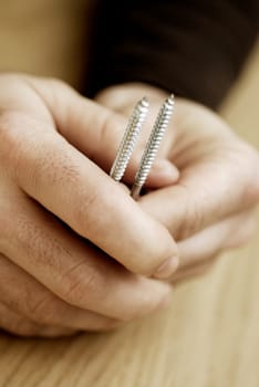 Close-up of a personŽs hands holding two screws