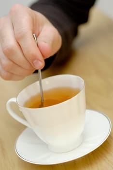 Close-up of a personŽs hand stirring tea with a teaspoon