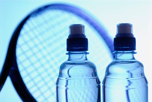 Close-up of two water bottles with a tennis racket