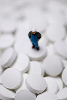Close_up of a human figurine on the heap of pills