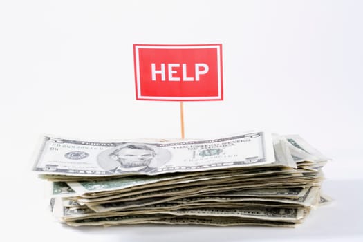 Close_up of a stack of us paper currency with a help signboard