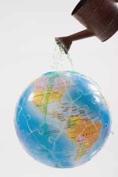 Close_up of a watering can watering on a globe