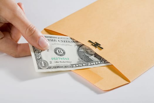 Close_up of a personŽs hand picking out a US dollar bill from an envelope