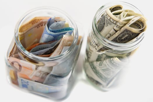 Euro and American bank notes squashed into two jars