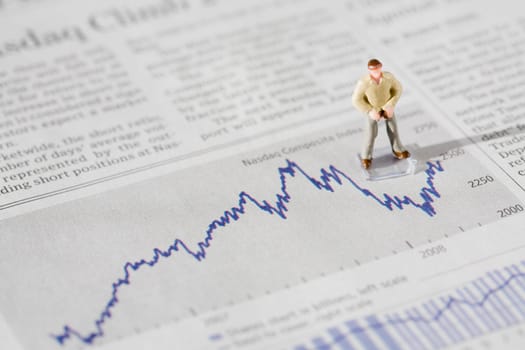 Figurine of a businessman standing on a financial newspaper