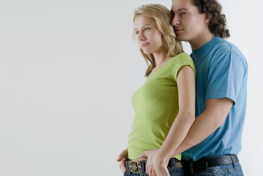 Side profile of a young man embracing a young woman from behind