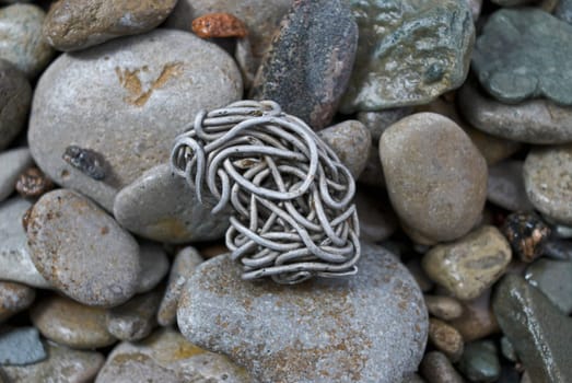 Close_up of a tangled aluminum wire on pebbles