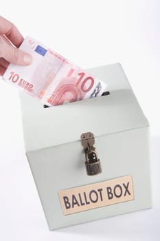 Close_up of a personŽs hand inserting ten euro banknote into a ballot box