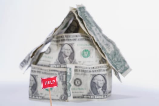 Help sign board in front of a miniature house made by US dollar bills